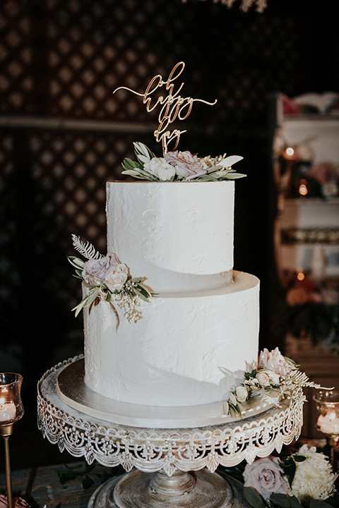 white two-tiered cake with light pink floral detailing