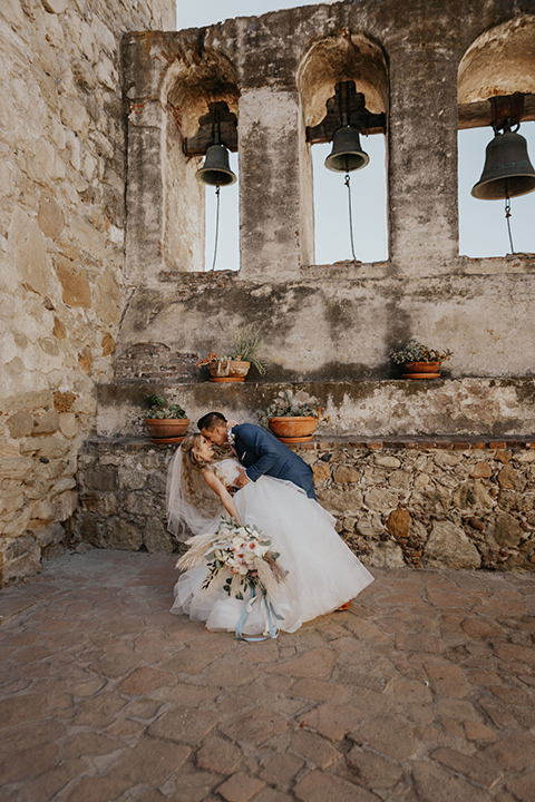 bride in a white ballgown with a lace bodice and the groom in a dark blue suit and light pink long tie