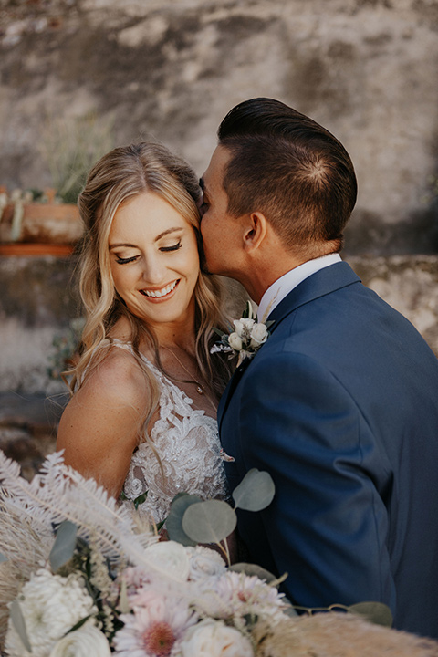 bride in a white ballgown and lace bodive and the groom in a dark blue suit with a light pink suit