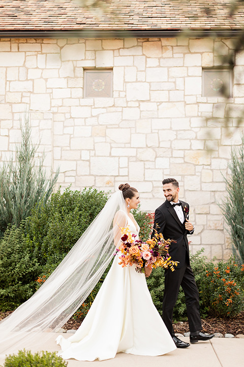  old world wedding at Allegretto Vineyard Resort – bride in a long gown with a cutout back design and the groom in black tuxedo with a black diamond bow tie at ceremony