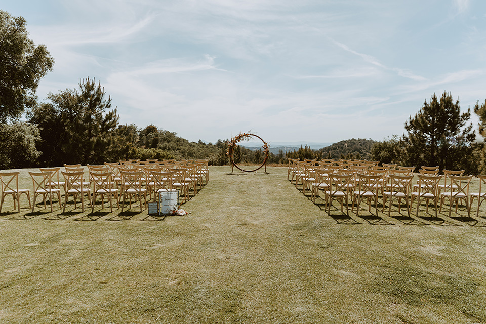  the bridesmaids in deep orange gowns, the groomsmen in navy suits, and the bride in an ivory rue de sine gown and the groom in a dark blue suit with an orange tie at the ceremony