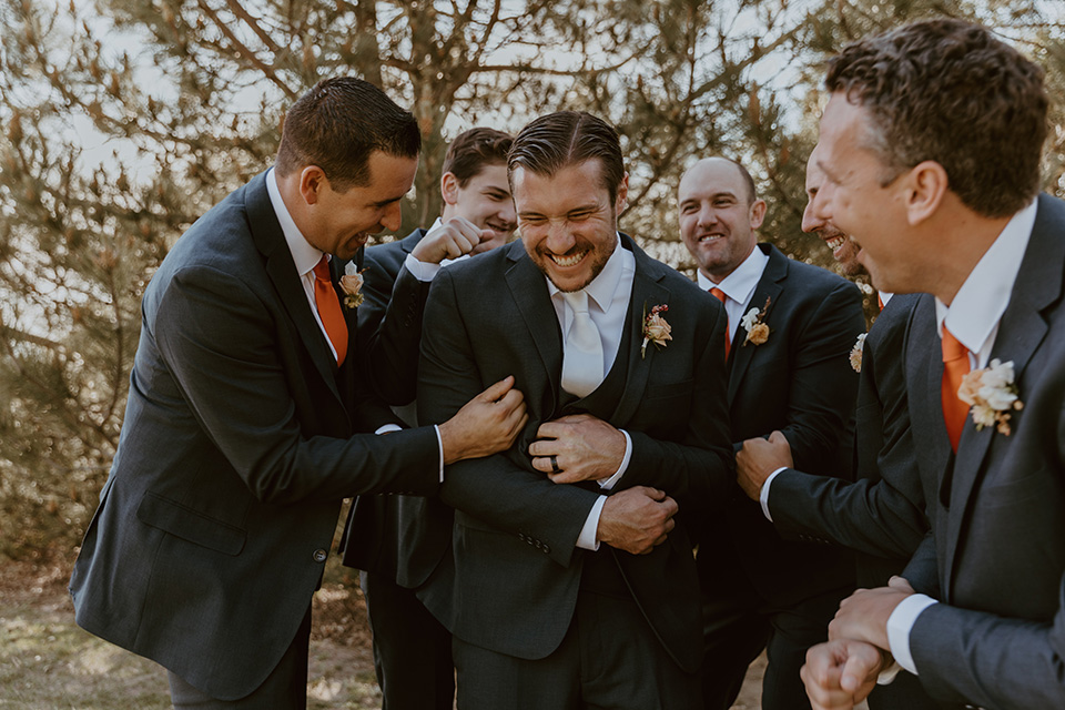  groom and groomsmen in dark blue suits with orange long ties 