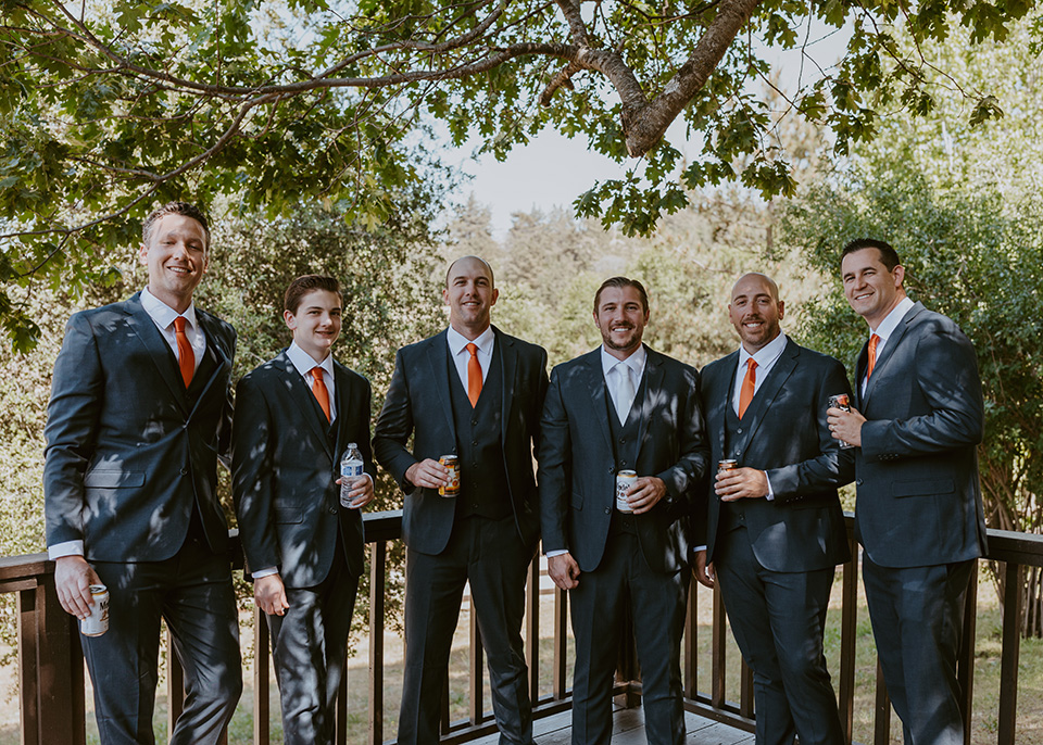  groom and groomsmen in dark blue suits with orange long ties 
