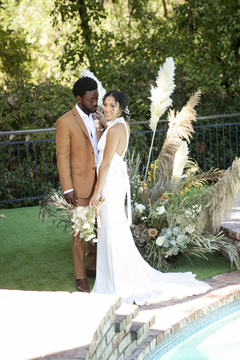  backyard bohemian elopements with the bride in a high neckline gown and the groom in a caramel suit -ceremony