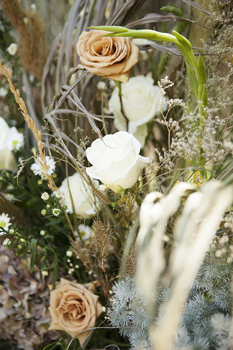  backyard bohemian elopements with the bride in a high neckline gown and the groom in a caramel suit -flowers 