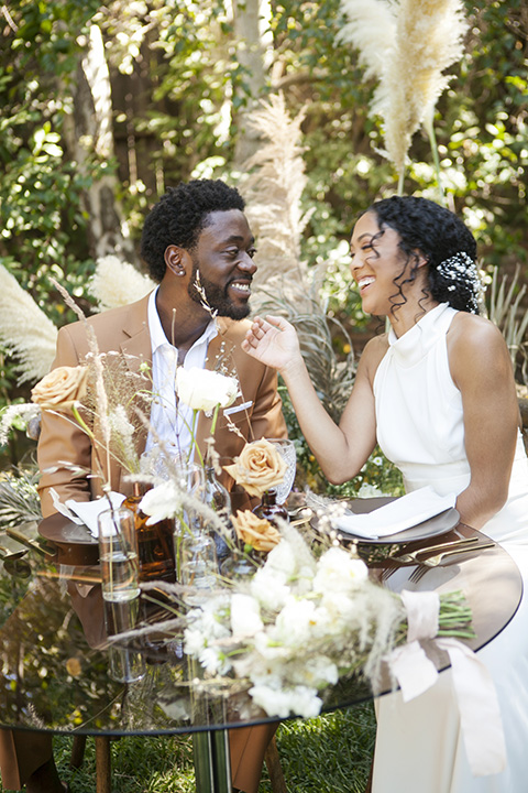  backyard bohemian elopements with the bride in a high neckline gown and the groom in a caramel suit -sitting 