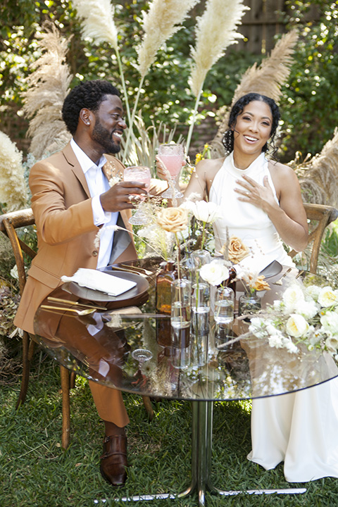  backyard bohemian elopements with the bride in a high neckline gown and the groom in a caramel suit -cheers 