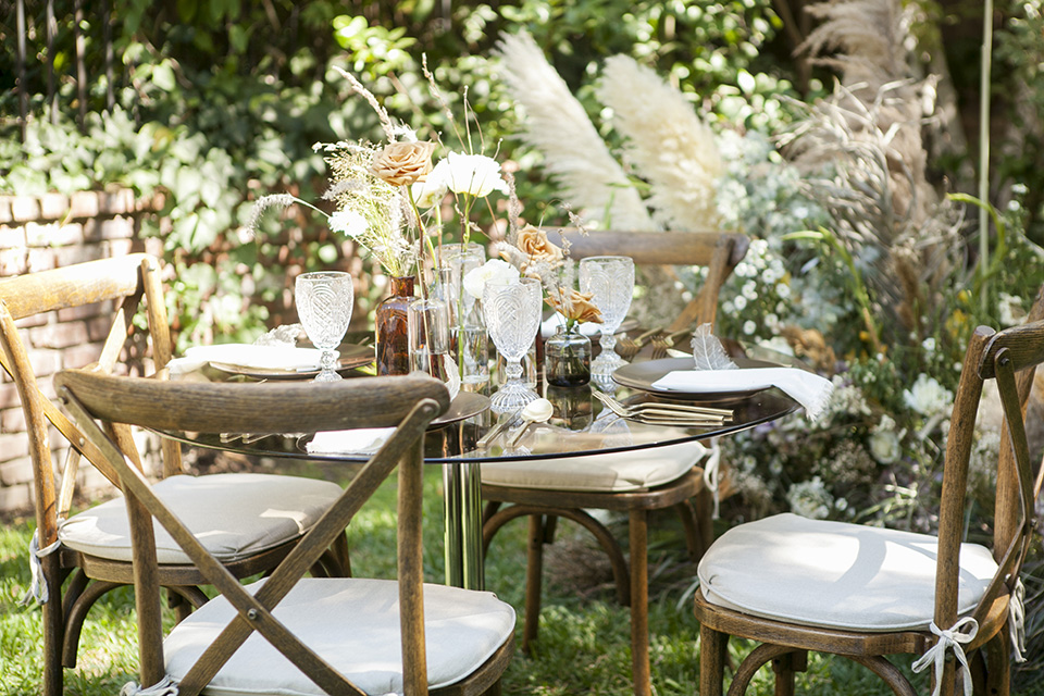  backyard bohemian elopements with the bride in a high neckline gown and the groom in a caramel suit -table 