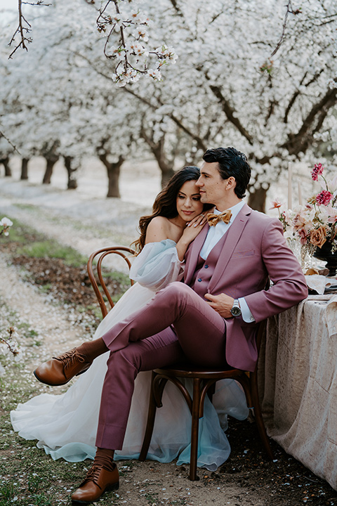   bride in a pastel pink and blue gown and the groom in a rose pink suit and gold bow tie