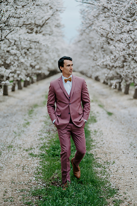  bride in a pastel pink and blue gown and the groom in a rose pink suit and gold bow tie 