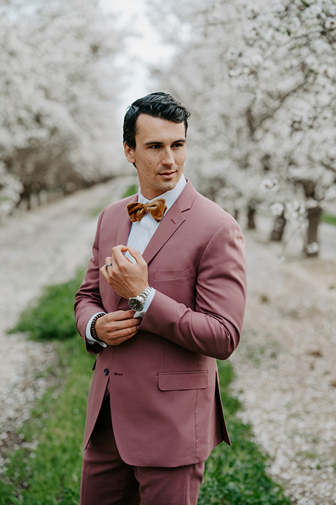   bride in a pastel pink and blue gown and the groom in a rose pink suit and gold bow tie