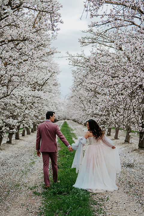  bride in a pastel pink and blue gown and the groom in a rose pink suit and gold bow tie 