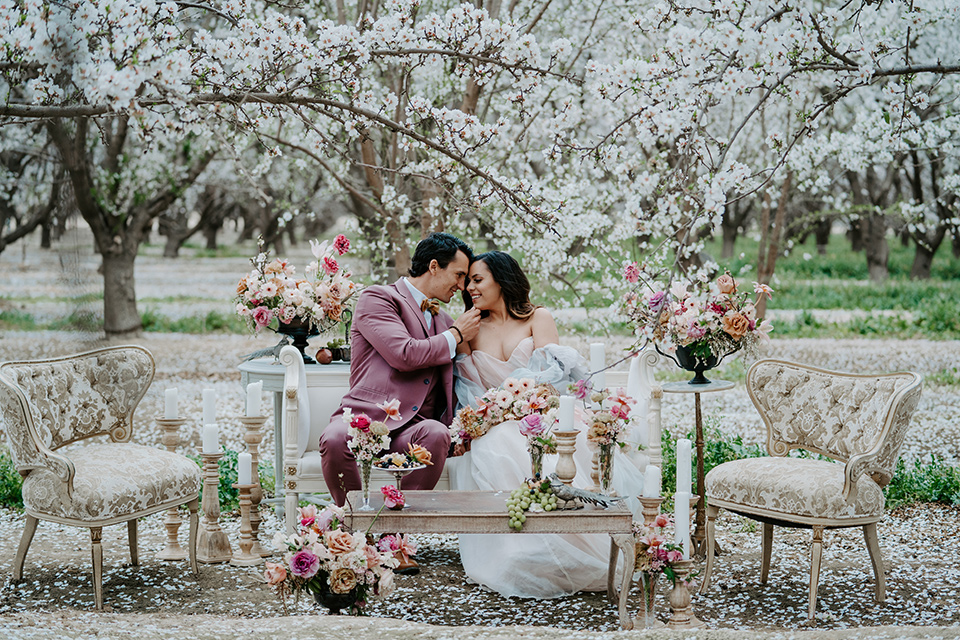  bride in a pastel pink and blue gown and the groom in a rose pink suit and gold bow tie 