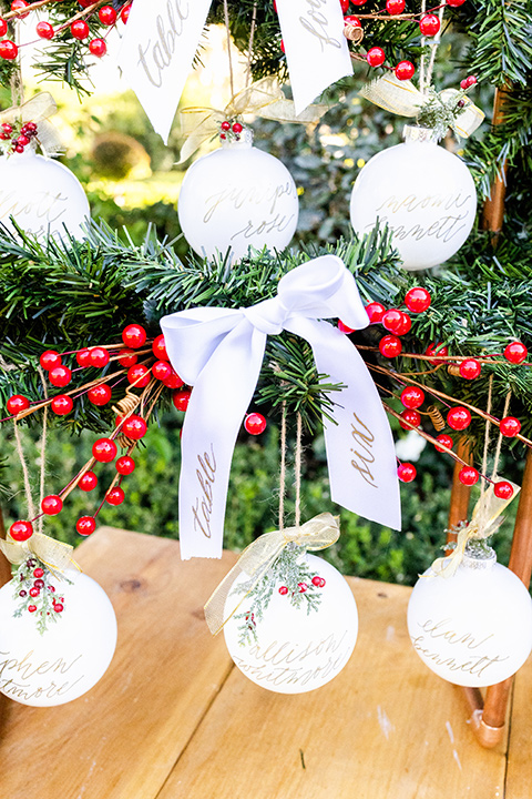  Christmas styled shoot with the groom in a burgundy velvet tuxedo and black pants  and the bride in a white long formfitting gown and long sleeves 