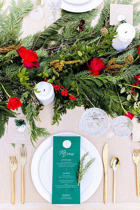  Christmas styled shoot with the groom in a burgundy velvet tuxedo and black pants  and the bride in a white long formfitting gown and long sleeves