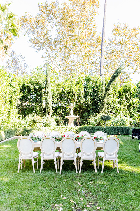  Christmas styled shoot with the groom in a burgundy velvet tuxedo and black pants  and the bride in a white long formfitting gown and long sleeves 