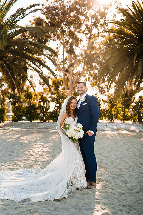  beach inspired wedding with cobalt blue suits for the groom and groomsmen and the bride in a formfitting lace gown in huntington beach california 