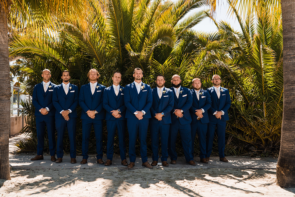  beach inspired wedding with cobalt blue suits for the groom and groomsmen and the bride in a formfitting lace gown in huntington beach california 