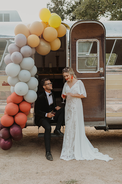  bride in a lace bohemian gown and the groom in an ivory paisley and burgundy ants and a bolo tie 