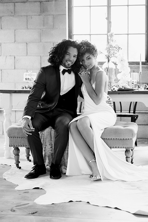  bride in a two-piece gown with her hair in a chic up-do and the groom in a charcoal tuxedo with a black lapel and a black bow tie 