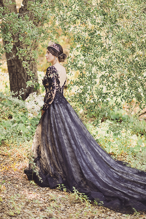  bride in a black lace gown and the groom in a green velvet tuxedo with a black bow tie and shoes 