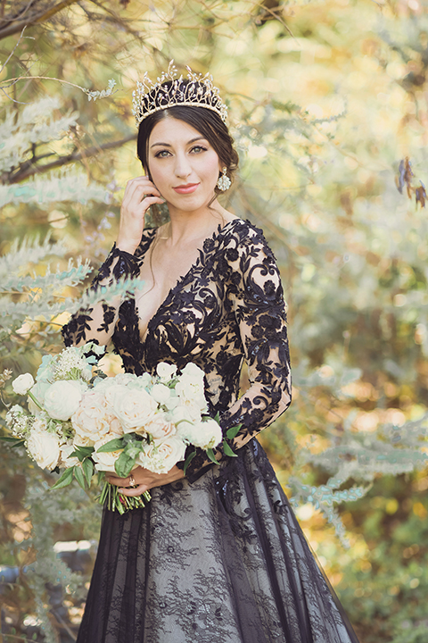  bride in a black lace gown and the groom in a green velvet tuxedo with a black bow tie and shoes 