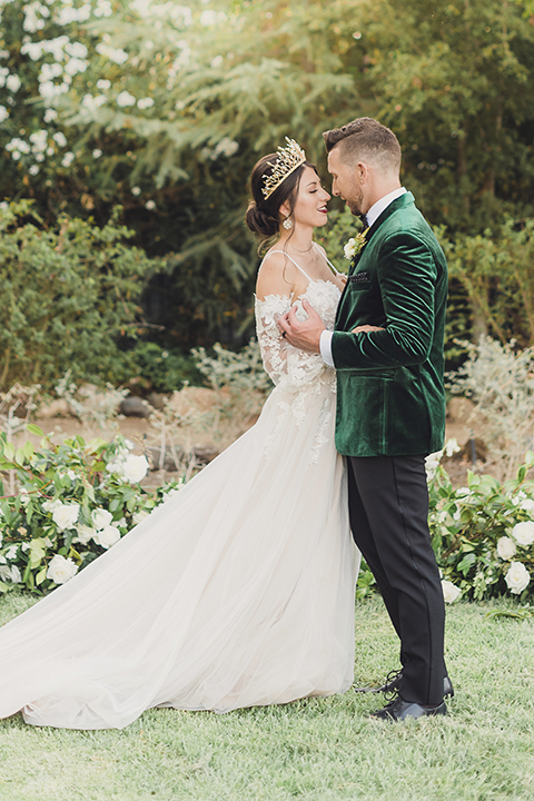  bride in a black lace gown and the groom in a green velvet tuxedo with a black bow tie and shoes 