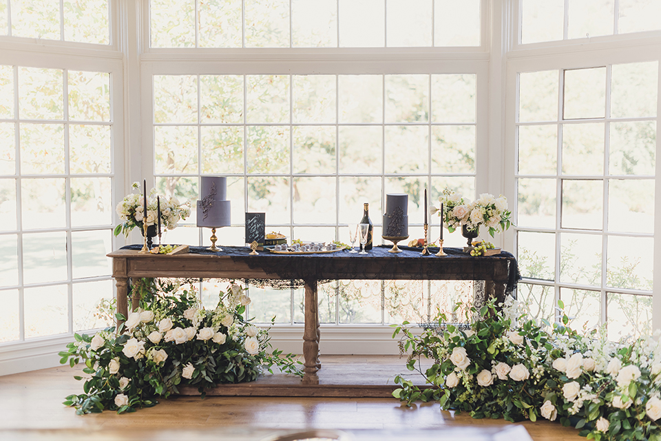  bride in a black lace gown and the groom in a green velvet tuxedo with a black bow tie and shoes 