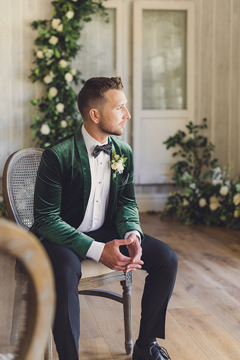  bride in a black lace gown and the groom in a green velvet tuxedo with a black bow tie and shoes 