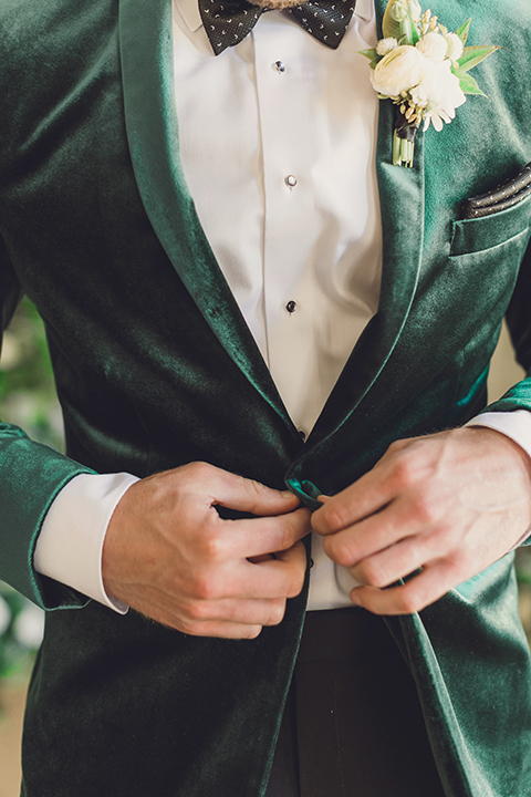  bride in a black lace gown and the groom in a green velvet tuxedo with a black bow tie and shoes 