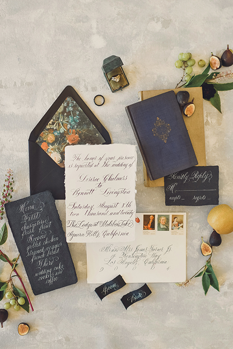  bride in a black lace gown and the groom in a green velvet tuxedo with a black bow tie and shoes 