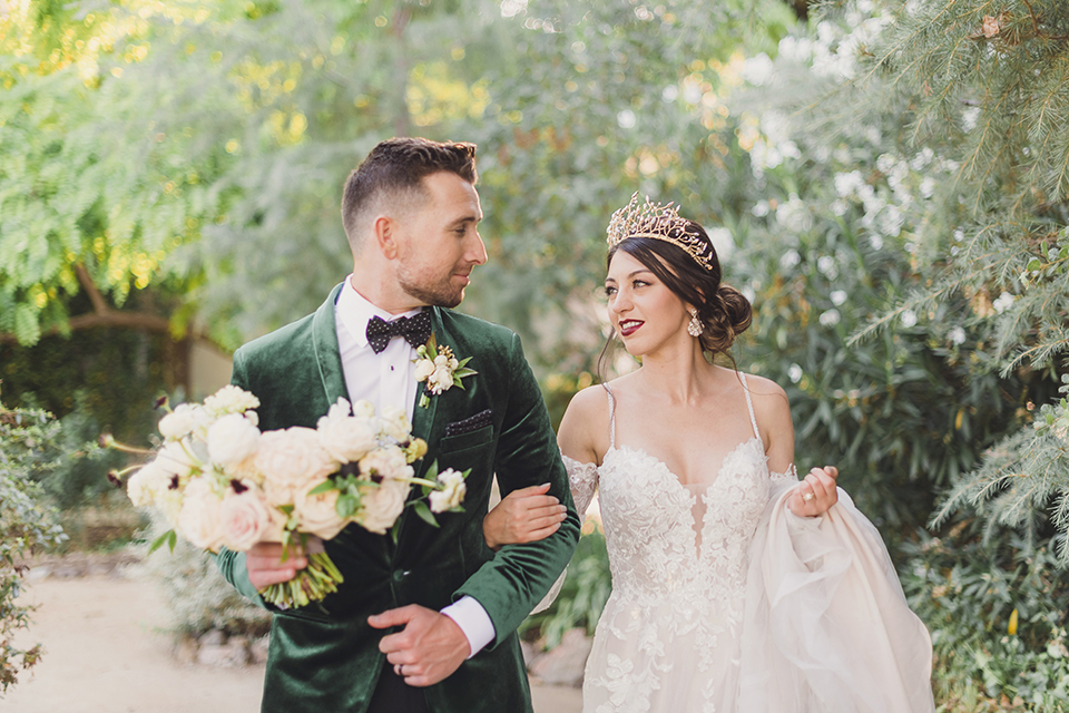  bride in a black lace gown and the groom in a green velvet tuxedo with a black bow tie and shoes 