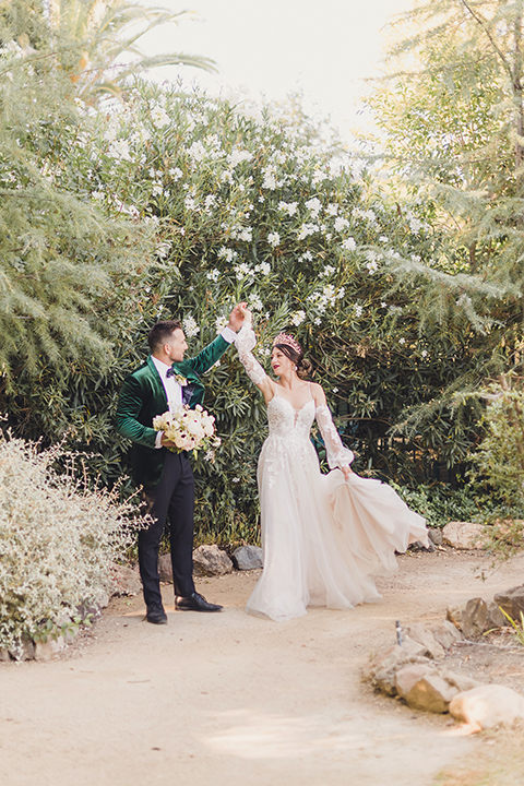  bride in a black lace gown and the groom in a green velvet tuxedo with a black bow tie and shoes 