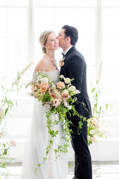  a modern black tie style wedding with the bride in a formfitting gown with a tulle off the shoulder 2 piece wedding gown and the groom in a black tuxedo 