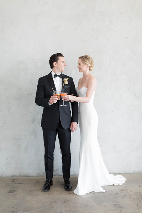  a modern black tie style wedding with the bride in a formfitting gown with a tulle off the shoulder 2 piece wedding gown and the groom in a black tuxedo