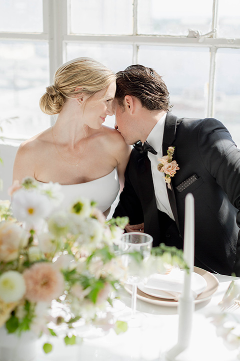  a modern black tie style wedding with the bride in a formfitting gown with a tulle off the shoulder 2 piece wedding gown and the groom in a black tuxedo