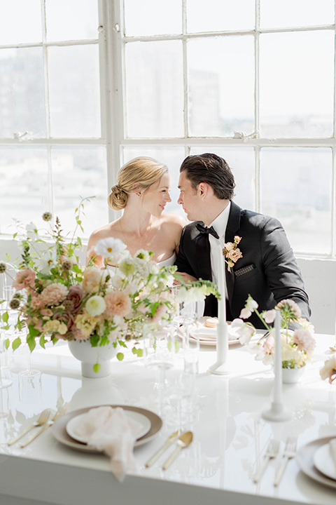  a modern black tie style wedding with the bride in a formfitting gown with a tulle off the shoulder 2 piece wedding gown and the groom in a black tuxedo 