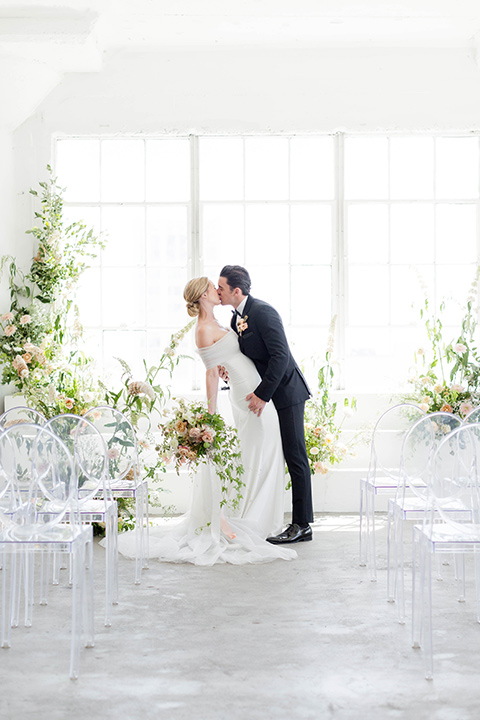  a modern black tie style wedding with the bride in a formfitting gown with a tulle off the shoulder 2 piece wedding gown and the groom in a black tuxedo