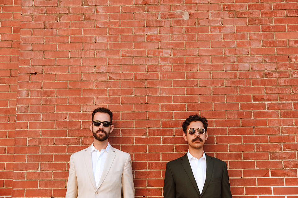  engagement shoot in long beach CA with one groom in a tan suit and the other groom in a green suit