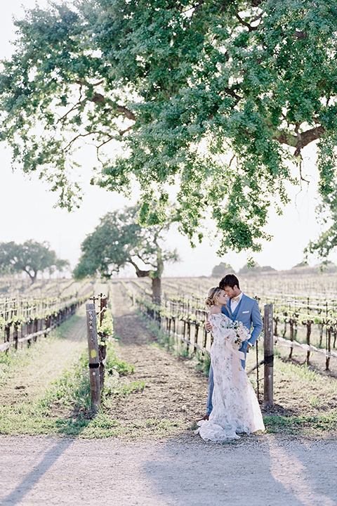  estate vineyard wedding with the bride in a floral gown and the groom in a light blue suit 