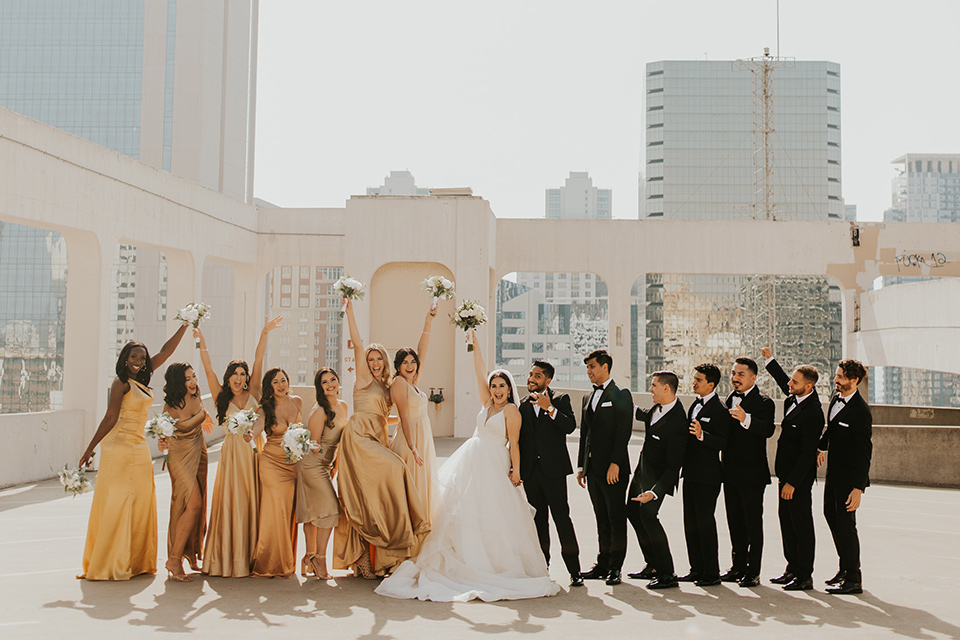  industrial wedding at the pannikin building in san diego with gold bridesmaids gowns and black tuxedos for the groom and groomsmen 