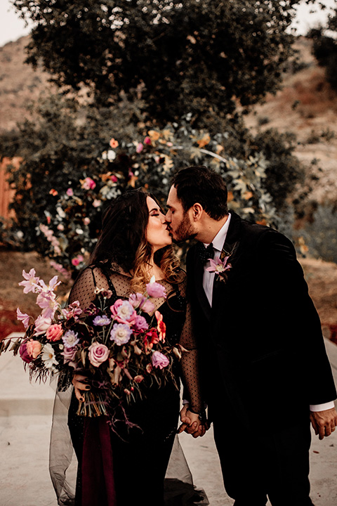  halloween inspired wedding with the groom in black velvet tuxedo bride in a black bridal gown with a pin dot overlay 