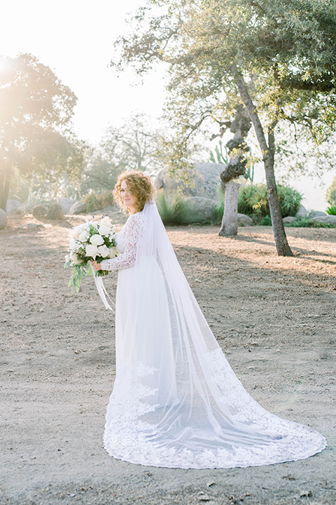  bride in a white gown with a long cape train and lace details