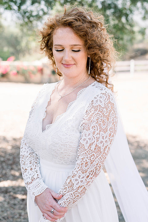  bride in a white gown with a long cape train and lace details 