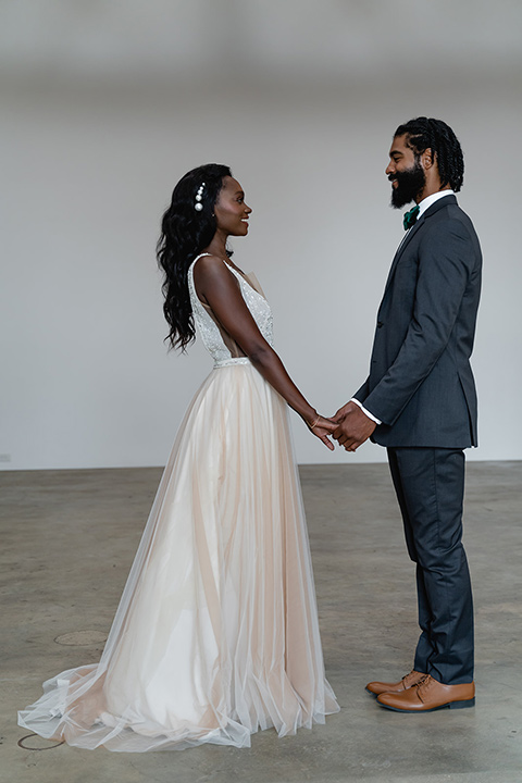  bride in a flowing white gown with a plunging neckline and the groom in a asphalt grey suit