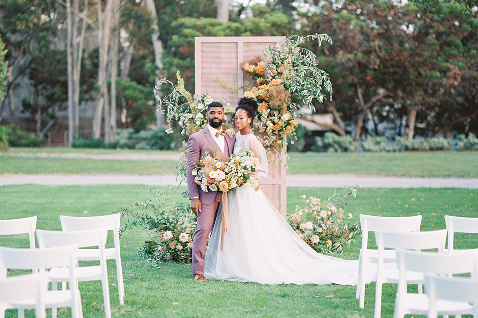  stunning chic pink and yellow wedding very french inspired, the bride is in a soft flowing gown with flutter sleeve and floral appliques and the groom in a rose pink suit with a gold velvet bow tie  
