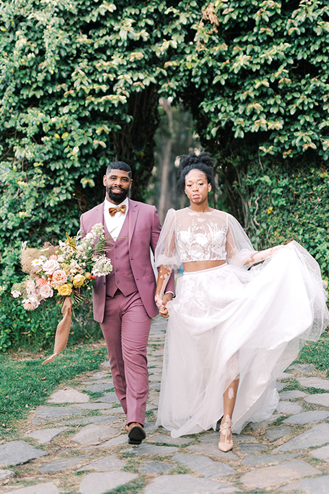  stunning chic pink and yellow wedding very french inspired, the bride is in a soft flowing gown with flutter sleeve and floral appliques and the groom in a rose pink suit with a gold velvet tuxedo  