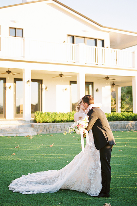  groom wearing black notch lapel tuxedo and the bride in a white fitted gown with a low back detail and lace accents 