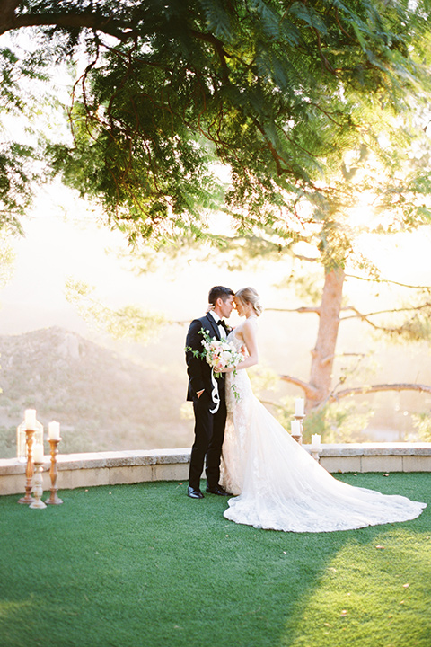  groom wearing black notch lapel tuxedo and the bride in a white fitted gown with a low back detail and lace accents 