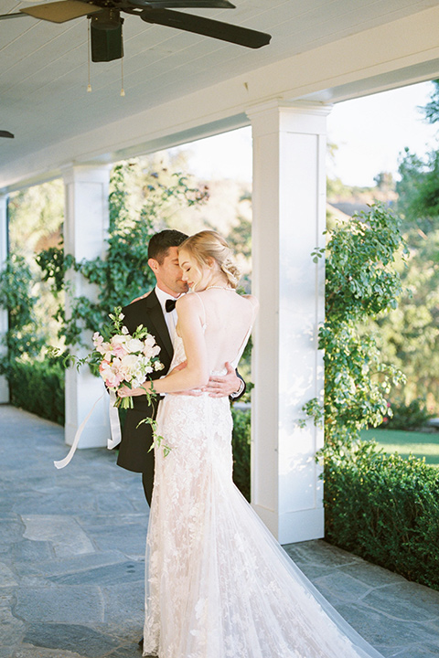  groom wearing black notch lapel tuxedo and the bride in a white fitted gown with a low back detail and lace accents 